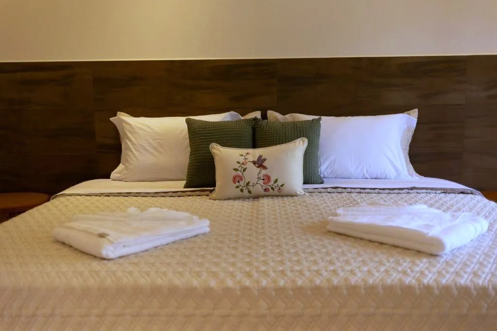 Almofada bordada com beija-flor sobre a cama