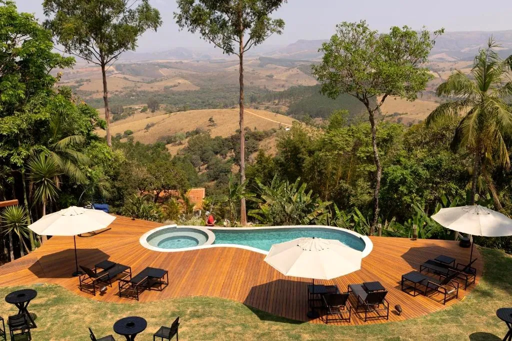 Piscina com deck de madeira e vista para o vale